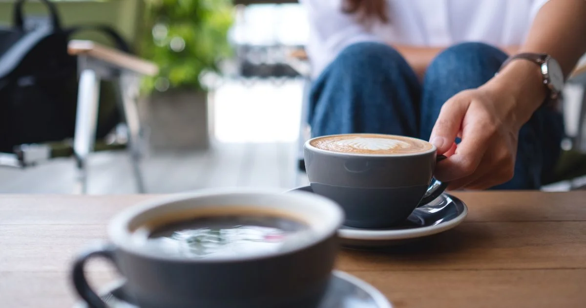 Person holding cup of coffee at café table