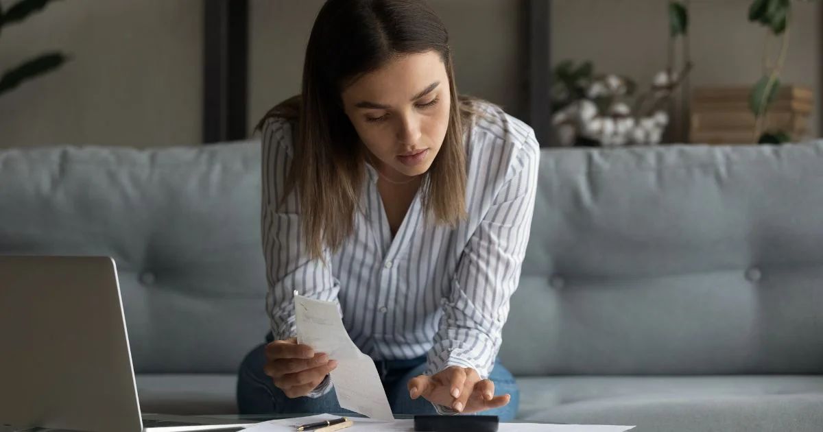 Woman reviewing bills and calculating expenses