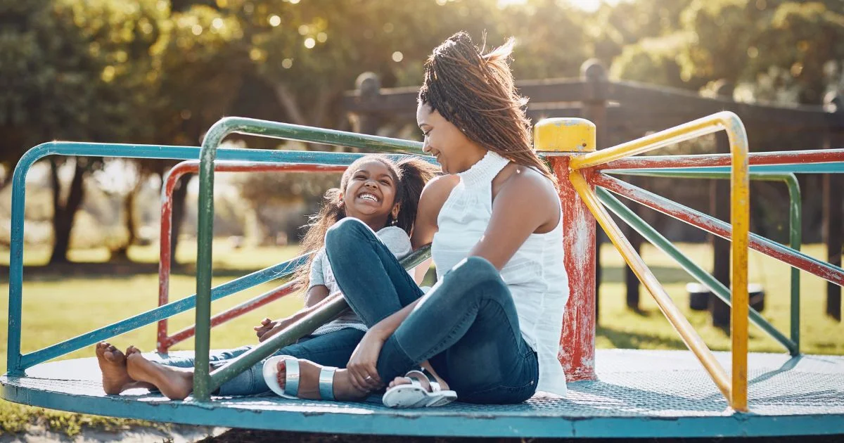 Mother and daughter playing at park smiling