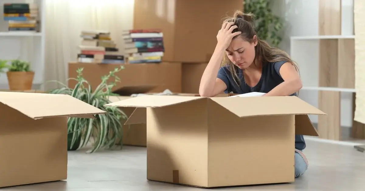 Stressed woman sitting among moving boxes during separation